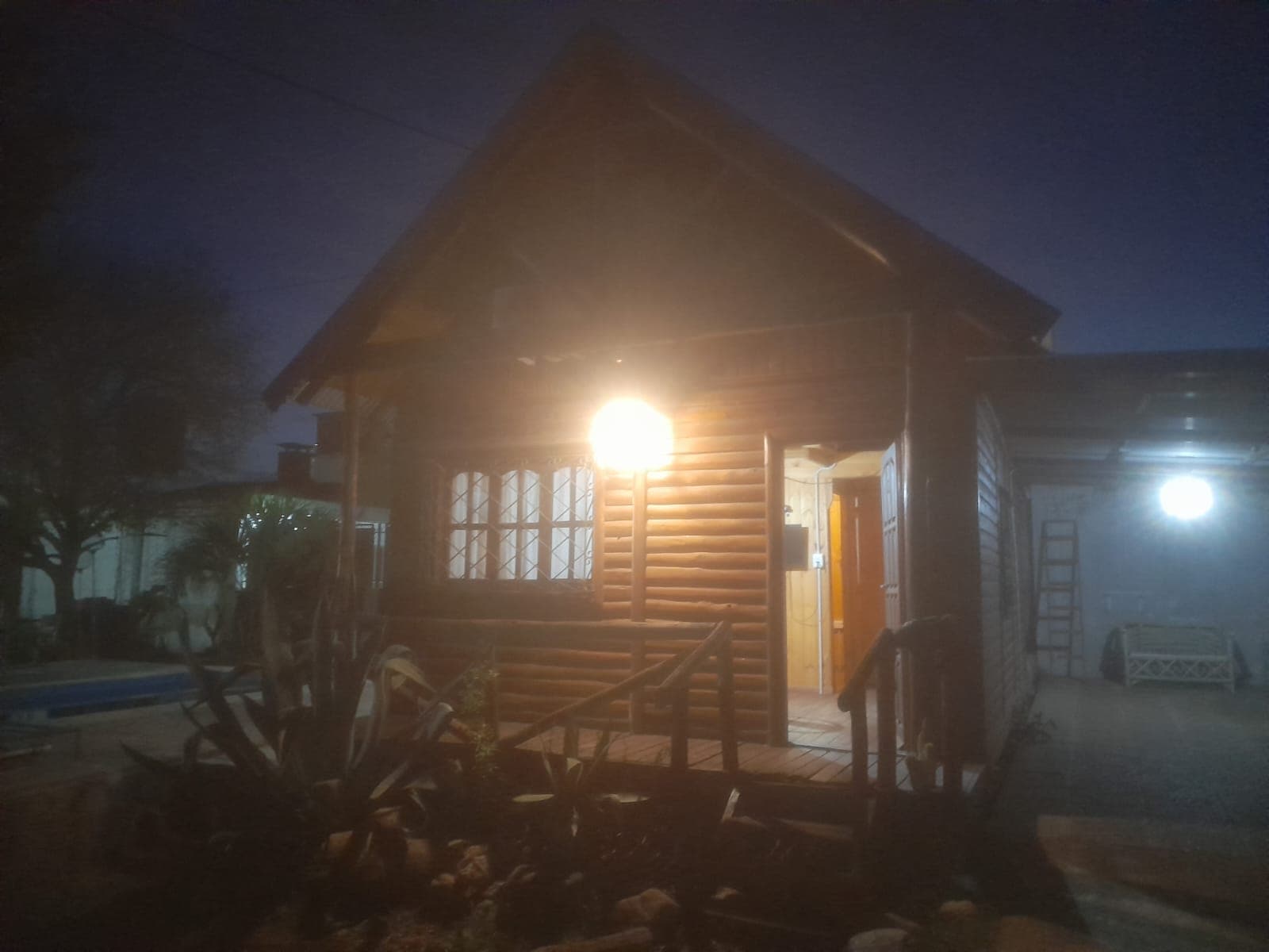 Vista frontal de noche cabaña con cochera